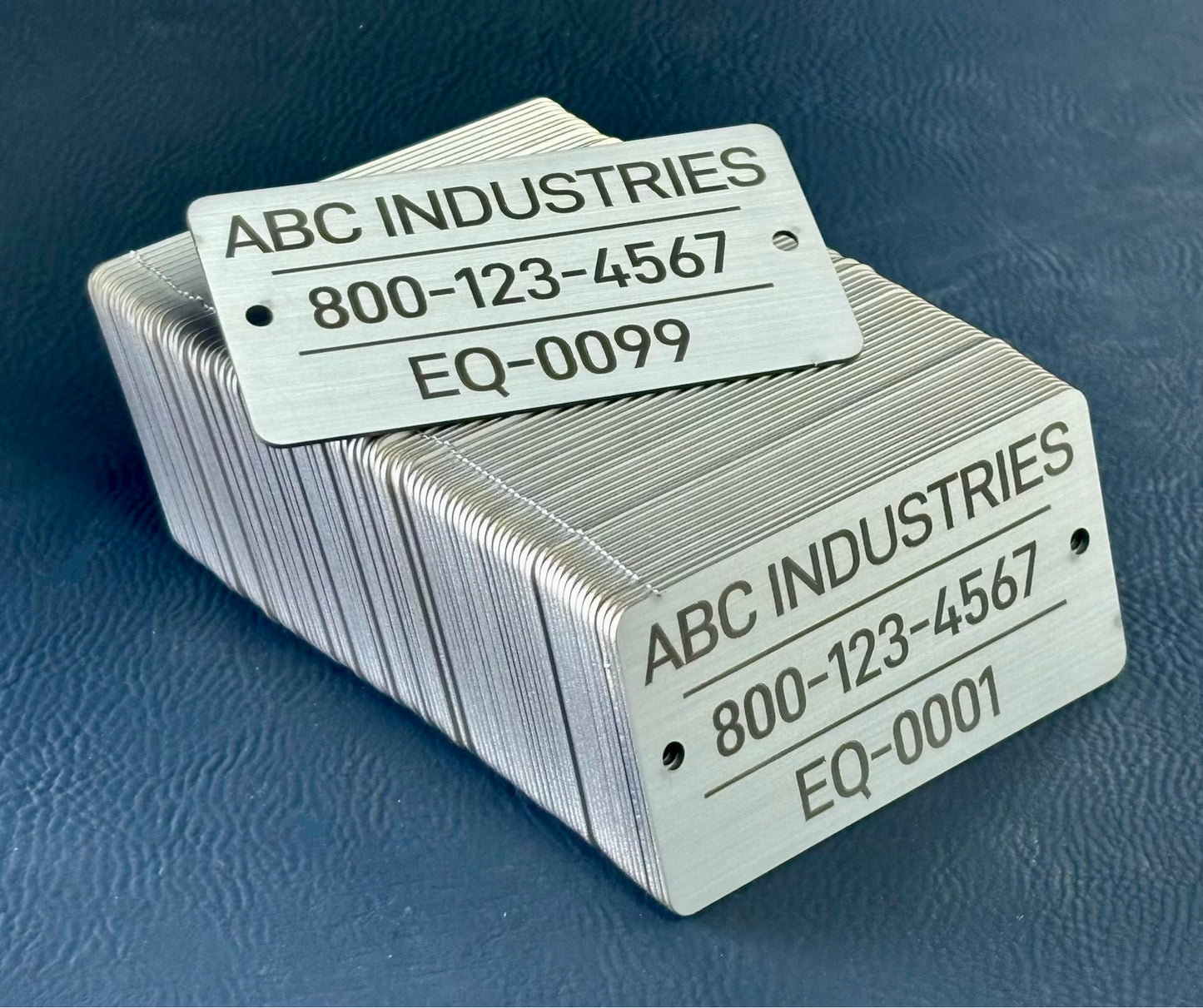 Sequencial numbered stack of metal tags with 'ABC Industries' branding and contact information on a blue background