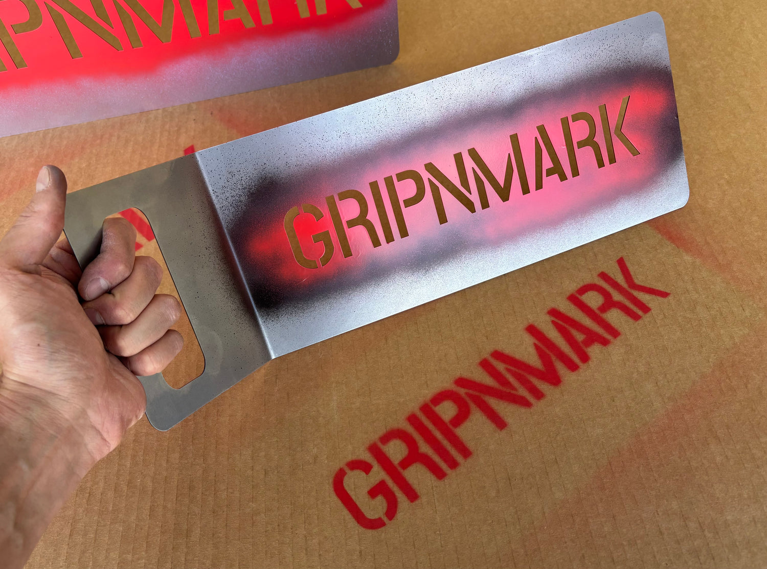 Hand holding GRIPNMARK steel stencil