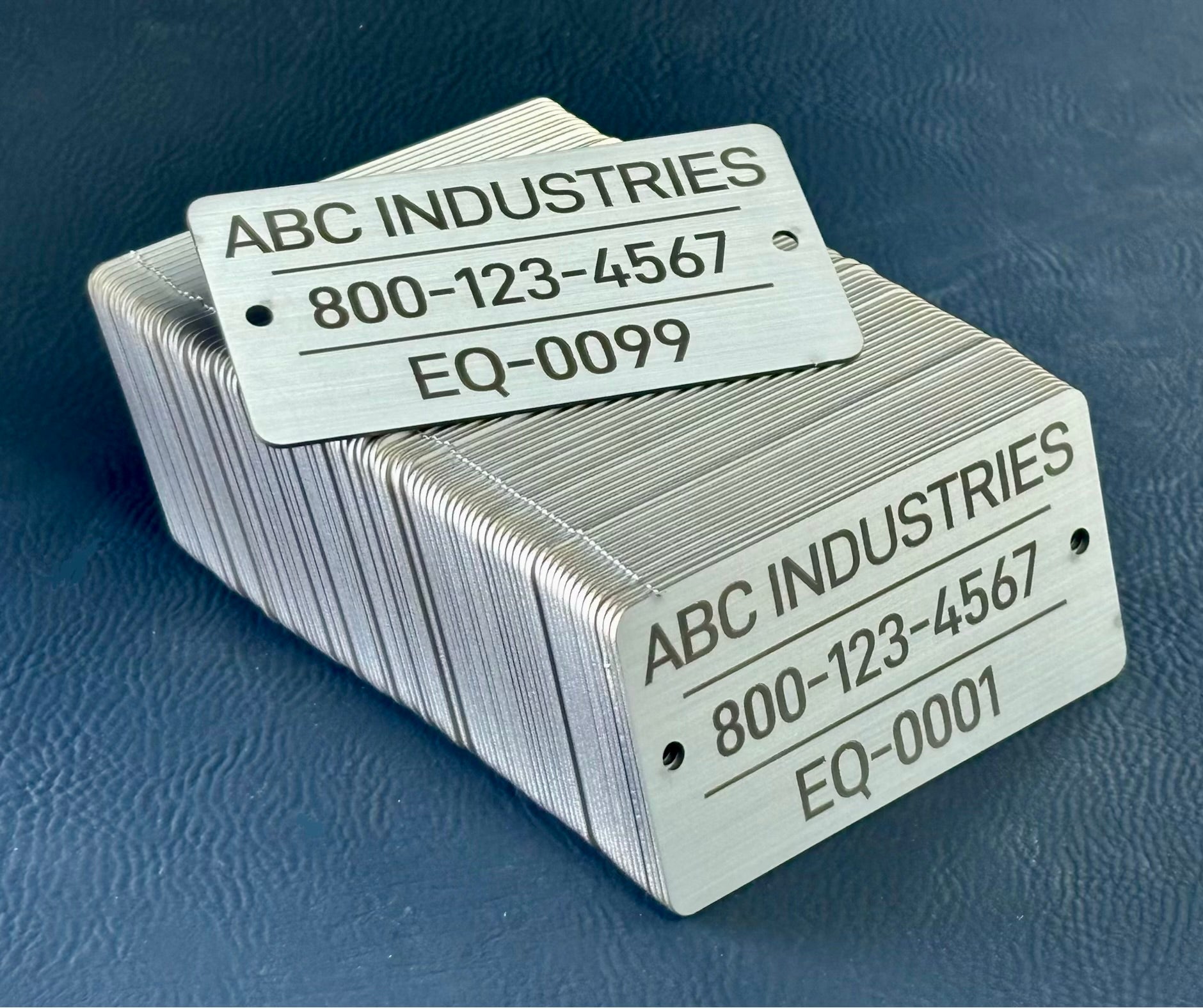 Sequencial numbered stack of metal tags with 'ABC Industries' branding and contact information on a blue background