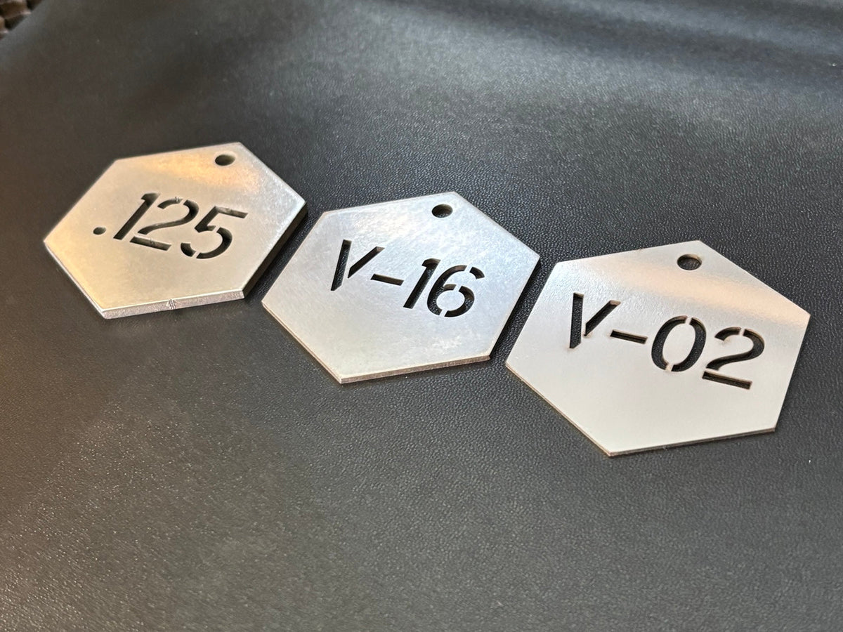 Group of hexagon stainless steel cut-through valve tags with custom identification codes