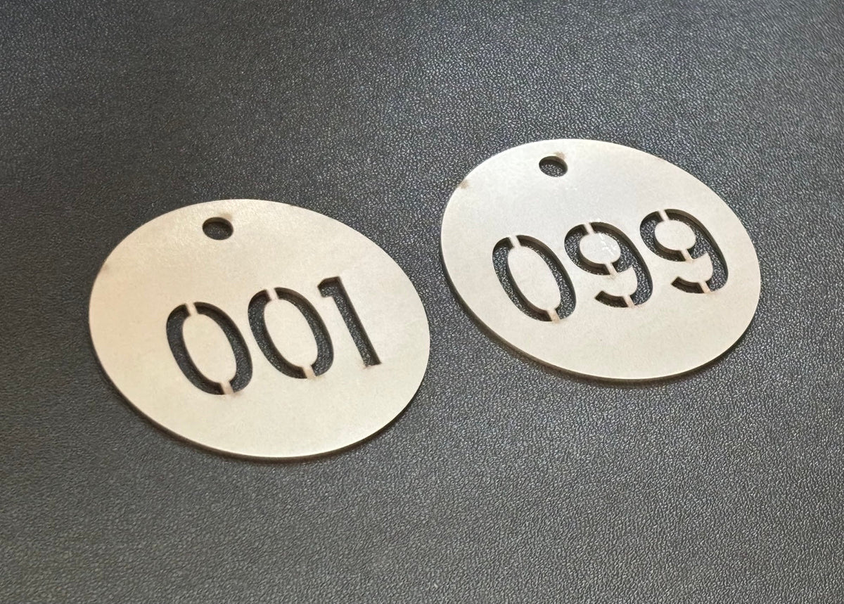 Two round stainless steel sequential cut-through valve tags marked 001 and 099